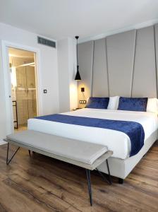 1 dormitorio con 1 cama blanca grande con almohadas azules en Taverna de la Sal Boutique Hotel, en L'Escala