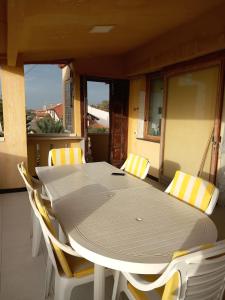 a table with yellow and white chairs on a balcony at Appartamenti Villa Wanda in Palmi