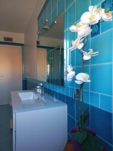 uma casa de banho em azulejos azuis com um lavatório e um espelho em A un passo da... B&B em Elmas