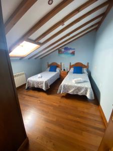 2 łóżka w pokoju z niebieskimi ścianami i drewnianą podłogą w obiekcie Casa Balmori El Peral w mieście Ribadedeva