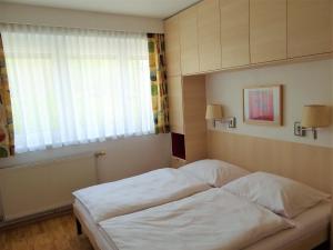 a bedroom with a white bed and a window at Appartements Margot in Krumpendorf am Wörthersee