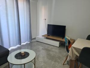 ein Wohnzimmer mit einem TV und einem Tisch in der Unterkunft Apartman Lena in Zadar