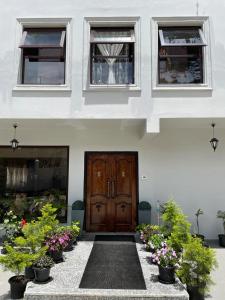 a front door of a white house with potted plants at The Arbour Inn in Shillong
