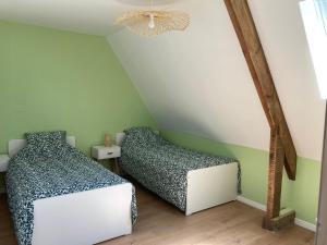 2 letti in una camera con pareti verdi e lampadario a braccio di Gîte de Kermoal-location de vacances a Poullan-sur-Mer