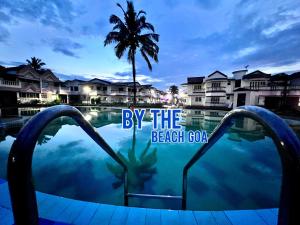 uma vista para uma piscina do resort com uma palmeira em LUSO Beach Homes Goa em Benaulim