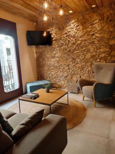 sala de estar con sofá, mesa y pared de piedra en Taverna de la Sal Boutique Hotel en L'Escala