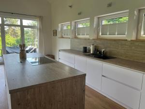 a kitchen with white cabinets and a sink and two windows at Forest Retreat- Serene 160m2 with Forest Views in Wermelskirchen