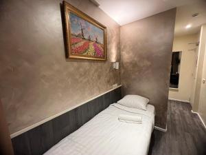 a small bed in a room with a painting on the wall at Orange Tulip Hotel in Amsterdam