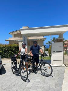 Villa Rocca - Rooms&SPA في بيتسو: رجل وامرأة يركبان الدراجات أمام المنزل