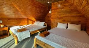 two beds in a room with wooden walls at Phu Nam House - Resort in Phú Quốc