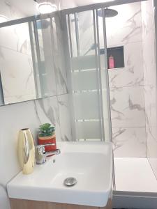 Un baño con lavabo blanco y ducha. en La MiMi des Minimes, en La Rochelle