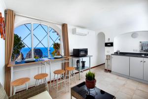 a kitchen with a counter with stools and a window at Faraglionensis MonaconeHouse Apartment in Capri