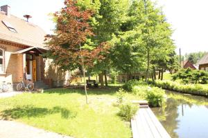 a house with a tree next to a river at Pension & Biergarten Spreewaldhof Leipe in Leipe