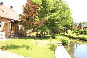una casa con un árbol al lado de un río en Pension & Biergarten Spreewaldhof Leipe, en Leipe