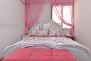 ein Schlafzimmer mit einem großen weißen Bett mit rosa Vorhängen in der Unterkunft Vila Apartments Lidija in Petrovac na Moru