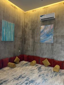 a living room with a red couch and two paintings at شاليهات كورال بارك in Al Kura