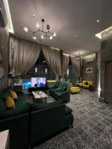 ein Wohnzimmer mit grünen Sofas und einem Flachbild-TV in der Unterkunft شاليهات كورال بارك in Al Kura