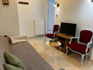 ein Wohnzimmer mit 3 roten Stühlen und einem TV in der Unterkunft Istos Apartment in Thessaloniki