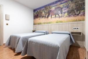 two beds in a room with a painting on the wall at Hostal Viñuela in San Pedro de Mérida