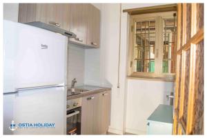 La cuisine est équipée d'un réfrigérateur blanc et d'un évier. dans l'établissement Ostia Holiday Paranzella, à Lido di Ostia