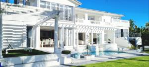 a white house with a swimming pool in front of it at Strode House in Knysna