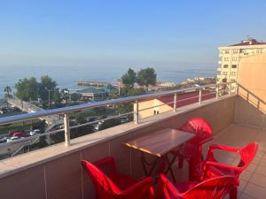 a balcony with red chairs and a table and the ocean at TOPCU HOME in Akcaabat