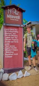 a man with a backpack standing next to a sign at Nilaveli Guest House in Nilaveli