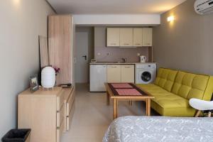 a living room with a yellow couch and a kitchen at Studio Treti Mart South in Primorsko