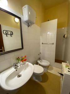 een badkamer met een wastafel, een toilet en een spiegel bij Podere San Biagio in Bagni San Filippo