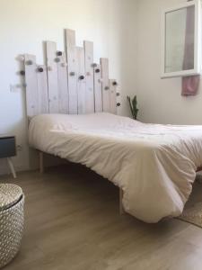 Cama blanca en habitación con cabecero de madera en Maison, piscine centreville Gujan-Mestras 4 hôtes, en Gujan-Mestras