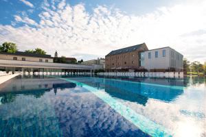 a large pool of water with buildings in the background at Hotel Castello & Thermal Spa Siklós in Siklós