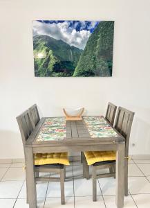 een houten tafel en stoelen met een schilderij aan de muur bij Kazalena in Saint-Pierre