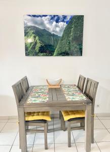 a wooden table and chairs with a painting on the wall at Kazalena in Saint-Pierre