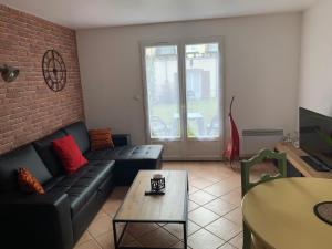 a living room with a black couch and a brick wall at Cottage Duplex golf de Limère prox Orléans in Ardon