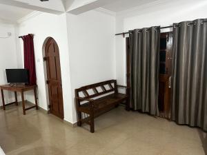 a room with a bench and a table and a television at Seaway inn guesthouse in Baga