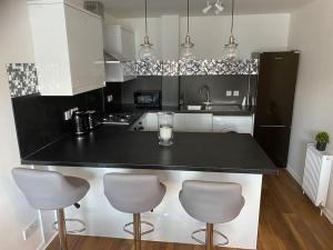 a kitchen with a black counter and three bar stools at Perfectly situated luxury 2 bedroom apartment in Glasgow