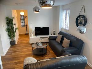 a living room with a couch and a tv at Perfectly situated luxury 2 bedroom apartment in Glasgow