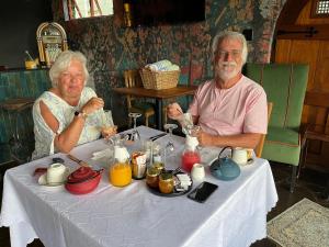 two older people sitting at a table with drinks at La Pension Guest House in Oudtshoorn