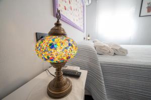 una lámpara colorida sentada en una mesa junto a una cama en DEL ARZOBISPO, en Plasencia