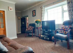 a living room with a couch and a flat screen tv at Farm View Cottage Castlerea in Castlerea