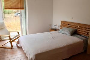 a bedroom with a bed and a chair and a window at Caper & Olive mountain cottage in Vathí