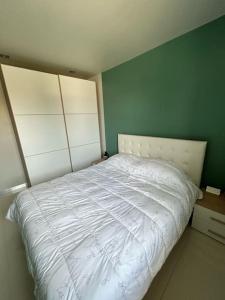 a bedroom with a white bed with a green wall at Appartamento Chloe in Sirmione