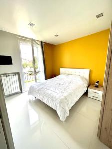 a bedroom with a white bed and a yellow wall at Appartamento Chloe in Sirmione
