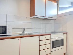 RødovreにあるOne Bedroom Apartment In Rdovre, Trnvej 41a,の白いキャビネット、シンク、電子レンジ付きのキッチンが備わります。