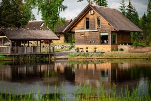 a wooden house with a pond in front of it at Rīti Siguldā in Stīveri