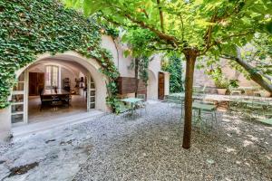 un patio con mesa, sillas y un árbol en Au Ralenti du Lierre en Beaumettes