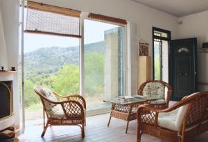 a living room with a table and chairs and a large window at Caper & Olive mountain cottage in Vathí