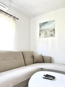 a living room with a couch and a remote control on a table at Apartman Misovic in Herceg-Novi