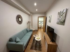 ein Wohnzimmer mit einem blauen Sofa und einem TV in der Unterkunft Apartamento Lujo centro histórico in Valladolid