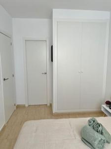 een witte slaapkamer met witte kasten en een bed bij Apto Olta 3 centro Campello piscina wifi parking in El Campello